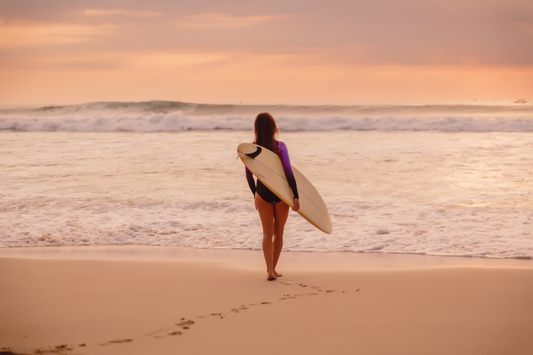 Surf girl with surfboard go to ocean for surfing at sunset